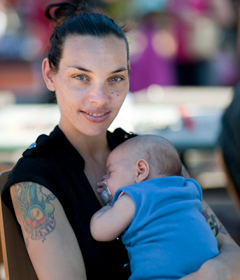 Smiling Indigenous Australian woman in her late twenties holding her baby of six weeks